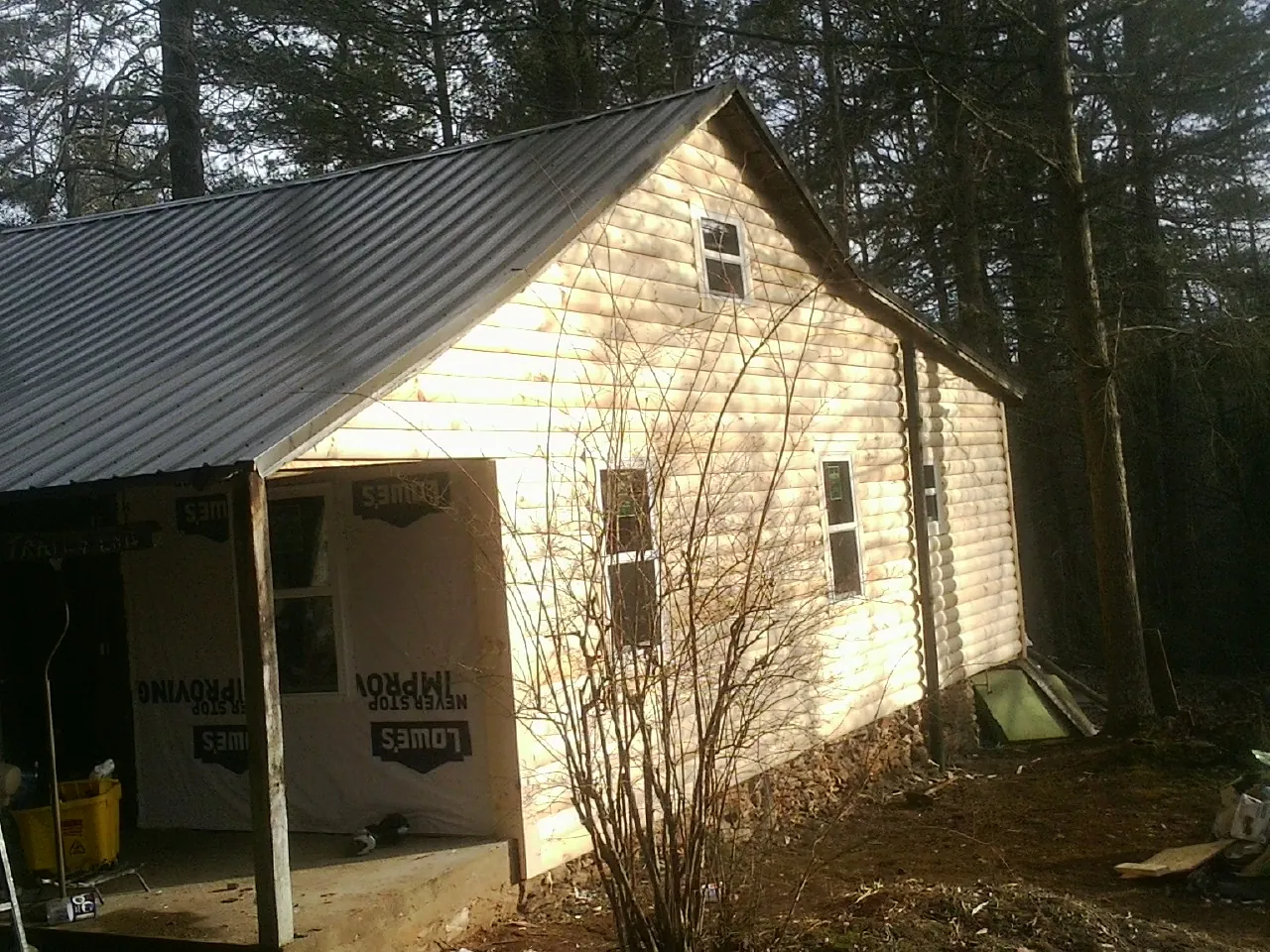 Log siding gable end under a dark metal roof edge in Leverett
