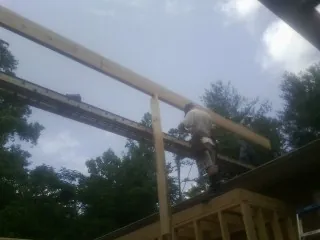 Carpenter setting a ridge beam over a new addition frame — Ice Dam Removal by Roofing Brothers in Leverett