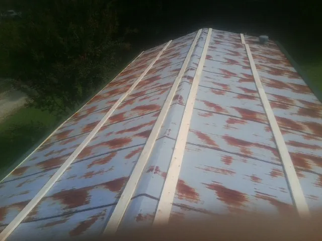Rusted metal roof panels with new wood purlins before replacement — Storm Damage Roof Repair in Leverett by Roofing Brothers