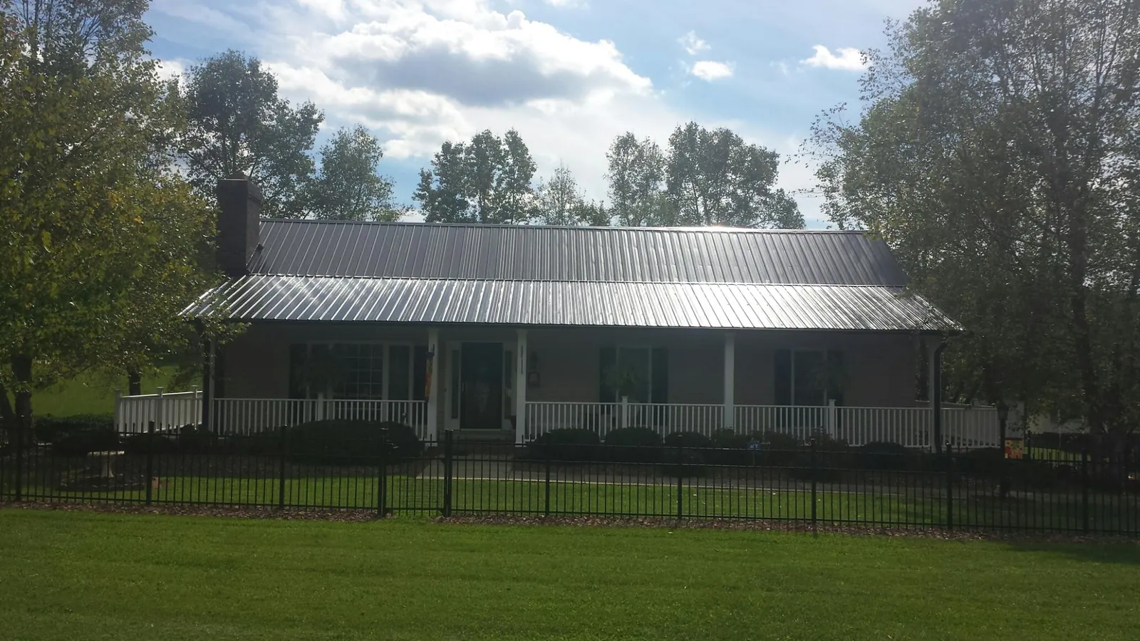 Gray metal roof on a brick ranch with a full width front porch — Gutter Guard Installation work by our crew in Leverett